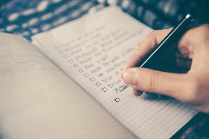 A hand ticking items on a handwritten list