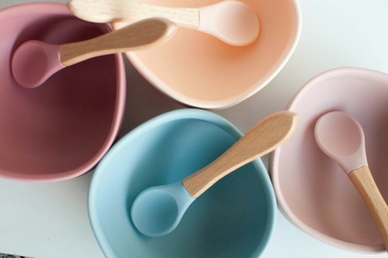 Small pastel bowls with wooden spoons, set out for a first meal