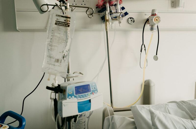 A hospital room with an infusion pump and an empty bed